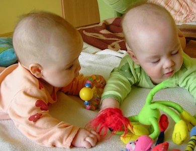 dwa niemowlaki bawią się zabawkami
